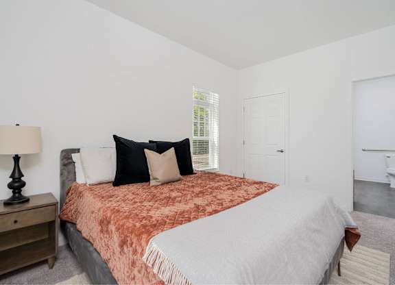 A bedroom with a bed, nightstand, and lamp.