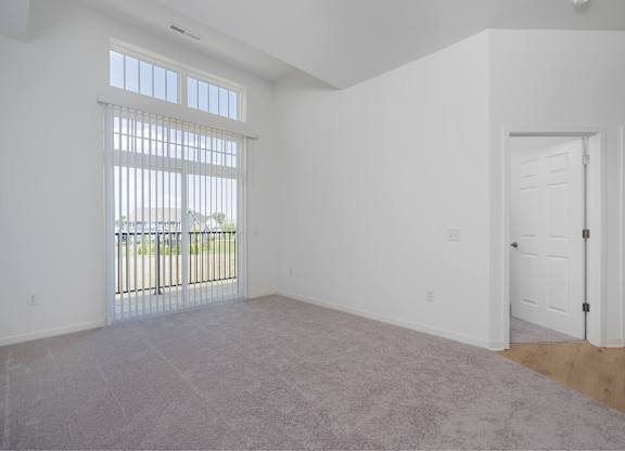 A room with a carpeted floor and a sliding glass door.