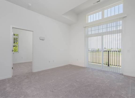 A large empty room with a window and a door.