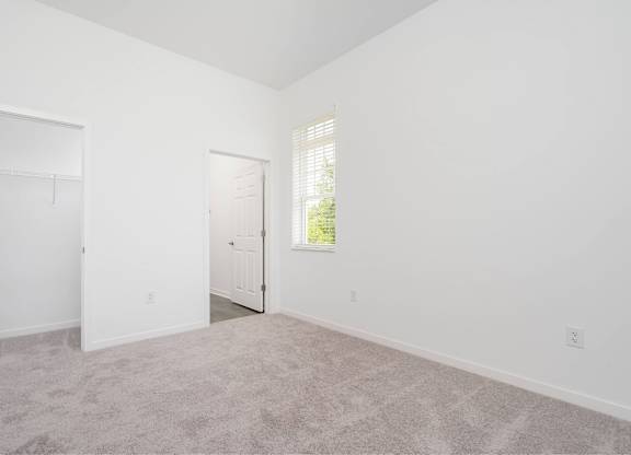 A room with a carpeted floor and two doors.