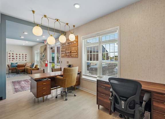 A room with a desk, chairs and a window.