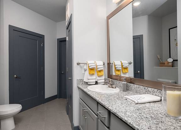 A bathroom with a toilet, sink, and mirror.