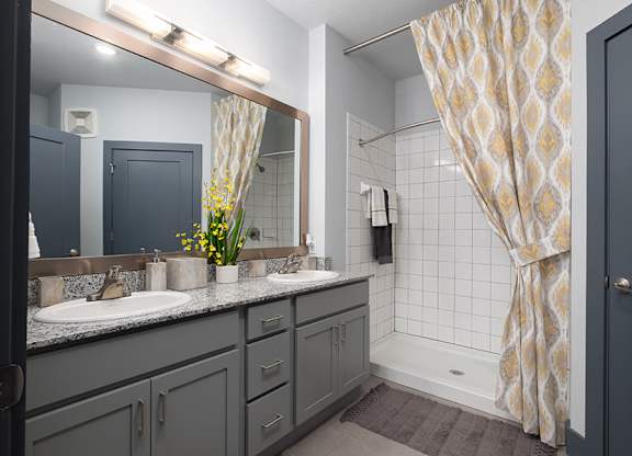 A bathroom with a sink, mirror, and shower.