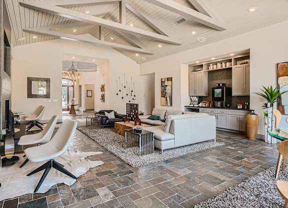 A modern living room with a stone floor and a high ceiling.