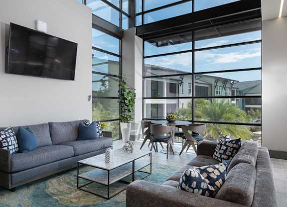 A living room with a grey couch and a flat screen TV mounted on the wall.