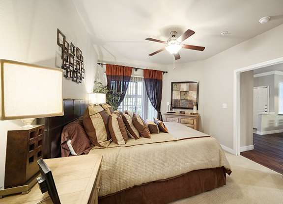 A bedroom with a bed, a ceiling fan, and a window with curtains.