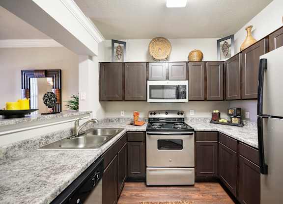 A kitchen with a stove, sink, and refrigerator.