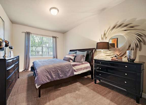 A bedroom with a bed, dresser, and mirror.