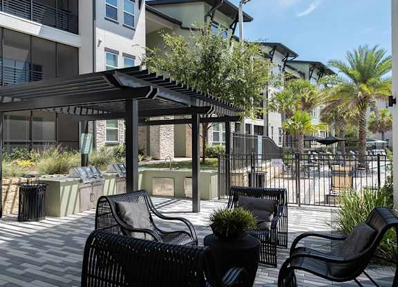 A patio with black chairs and a table under a black canopy.
