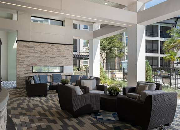 A patio with a black railing and a stone fireplace.
