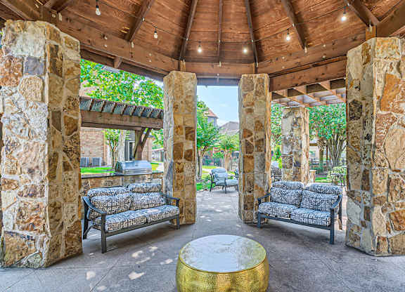 Stone pillars support a roof over a seating area.