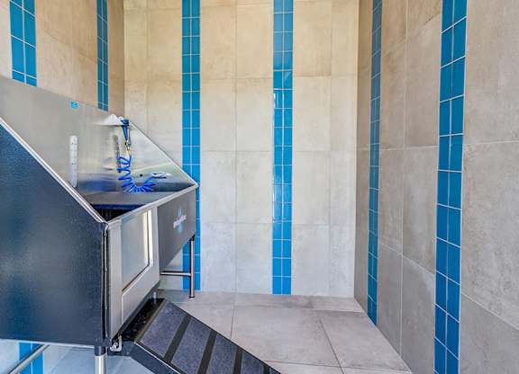 A black stainless steel sink in a bathroom with blue tiles.