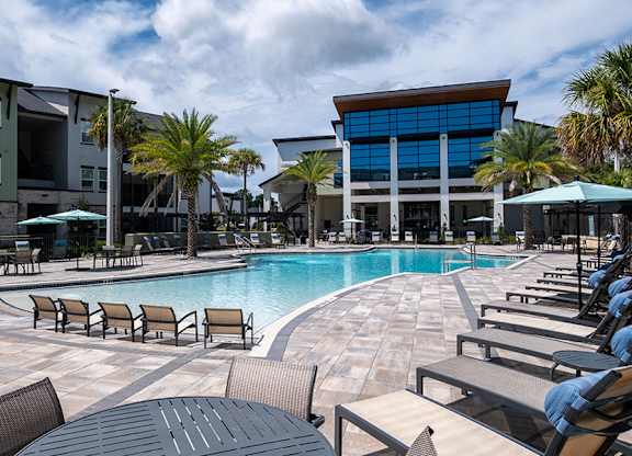 A large swimming pool surrounded by lounge chairs and umbrellas.