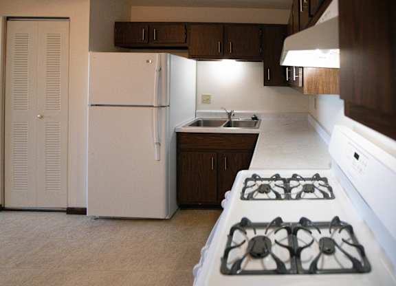 A white refrigerator is in a kitchen with a white stove.