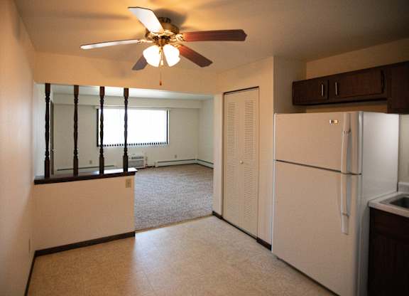 A white refrigerator sits in a kitchen next to a window.