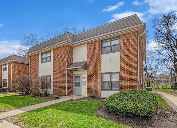 A brick apartment building with a green bush in front.