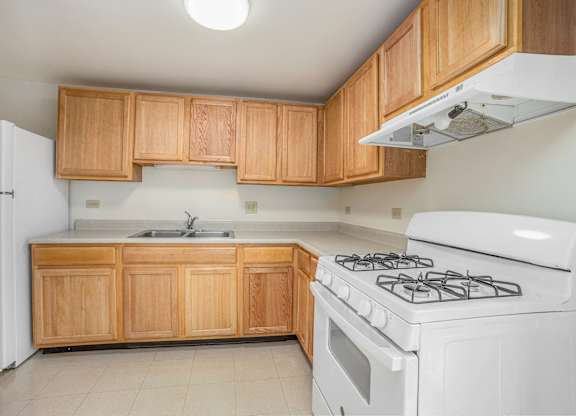 A kitchen with a white stove and wooden cabinets.