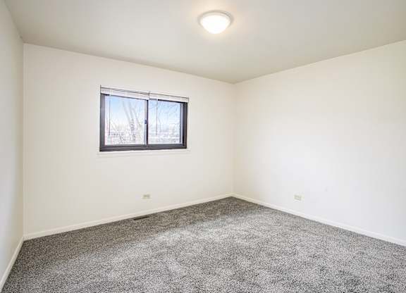 A room with a carpeted floor and a window.