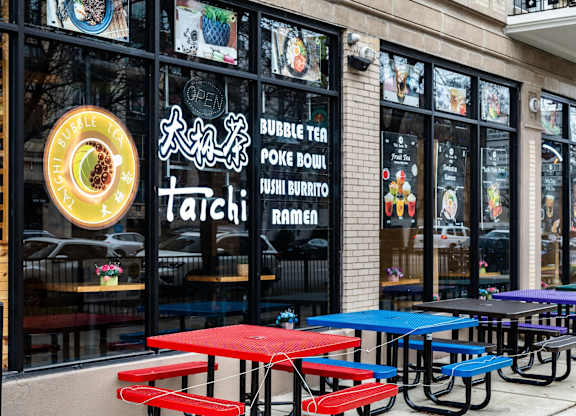 the exterior of a restaurant with red and blue tables
