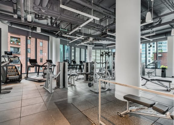 a gym with weights and cardio equipment in a building with tall windows  at Cassidy on Canal, Chicago, 60606
