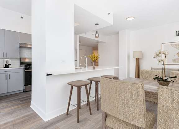 A kitchen with a bar area and a dining table with chairs.