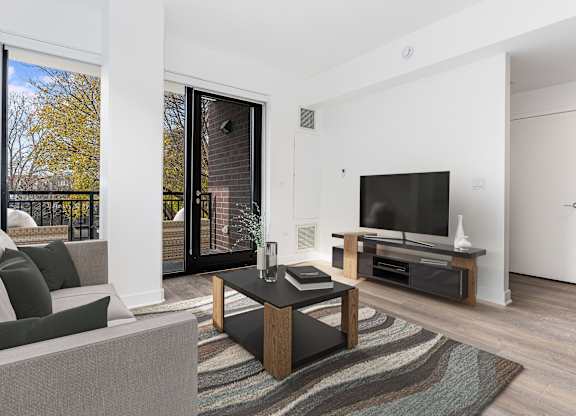 A modern living room with a grey sofa, a black coffee table, and a flat screen TV.