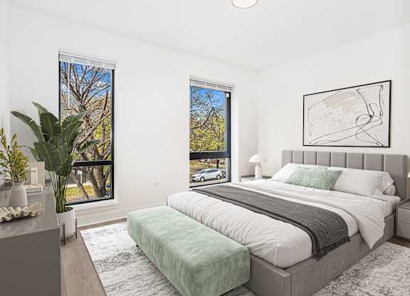 A bedroom with a large bed and a window overlooking a tree.