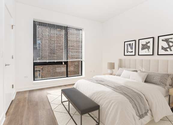 A bedroom with a large bed and a window with blinds.