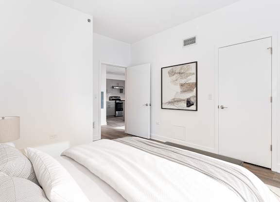 A bedroom with a large bed and a picture on the wall.