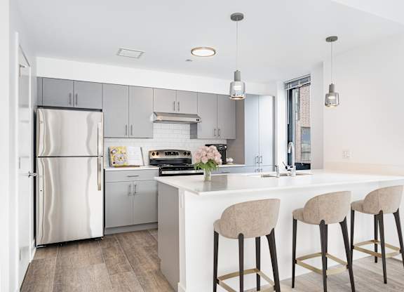 A kitchen with a white island and bar stools.