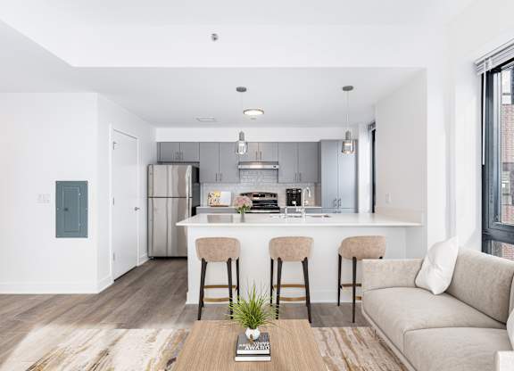A modern kitchen with a bar stool and a couch.