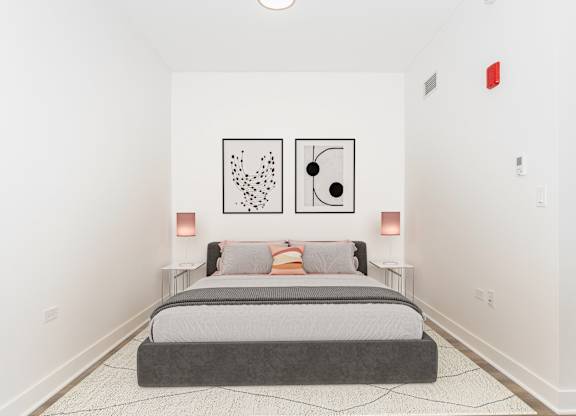 A bedroom with a bed, two lamps, and two framed artworks on the wall.