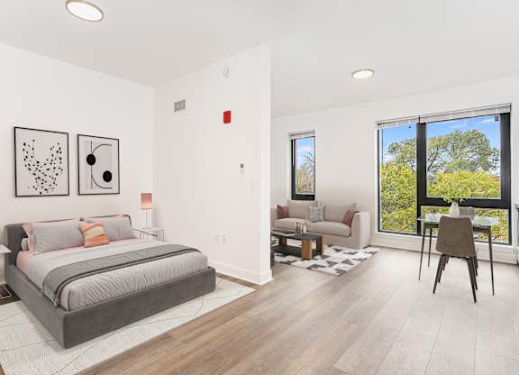 A bedroom with a large bed and a chair in front of a window.