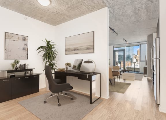 a home office with a desk and a view of a living room at One 333, Chicago