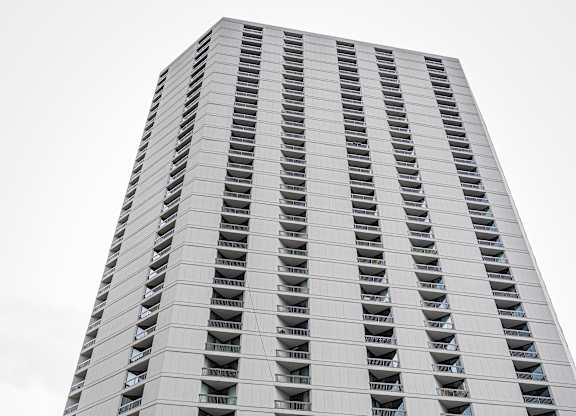 A tall building with a grey facade and balconies on the upper floors.