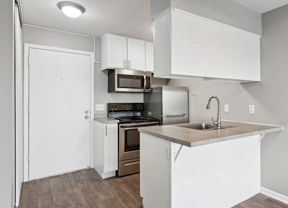 Compact kitchen with breakfast bar and modern appliances at Cedarvale Highlands Apartments, Eagan, MN