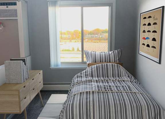 Bright bedroom with striped bedding and window view at Cedarvale Highlands Apartments, Eagan
