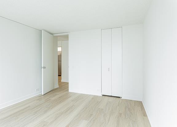 A white room with a wooden floor and a white door at Columbus Plaza, Chicago, Illinois