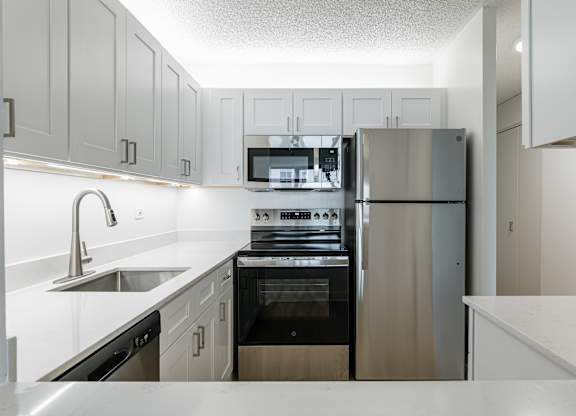 A modern kitchen with stainless steel appliances and white cabinetry at Columbus Plaza, Illinois, 60601