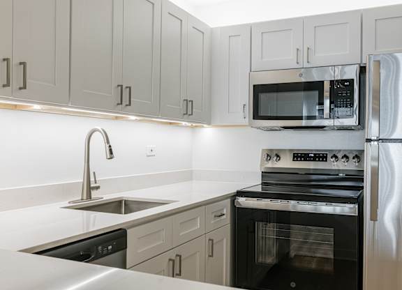 A modern kitchen with a stainless steel refrigerator, oven, and microwave at Columbus Plaza, Chicago, 60601