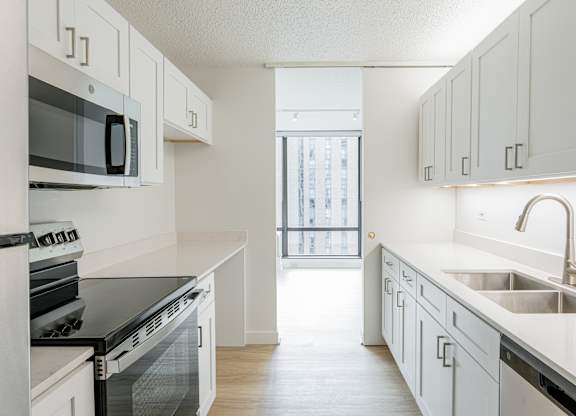 A kitchen with white cabinets and black appliances at Columbus Plaza, Chicago, Illinois
