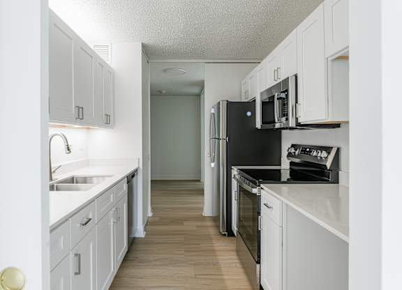 A kitchen with white cabinets and black appliances at Columbus Plaza, Chicago, 60601
