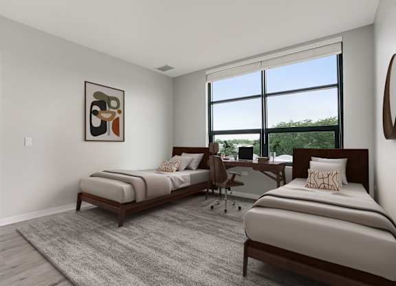 A bedroom with two beds and a desk with a chair.