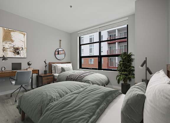 A bedroom with two beds, a desk, and a chair.