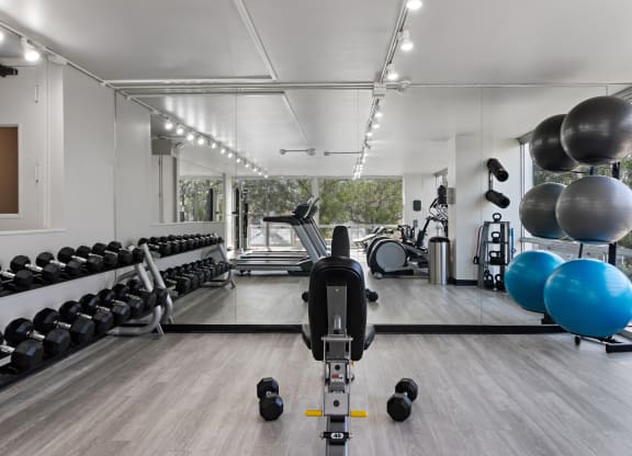 a gym with cardio equipment and weights on the floor and a large window at The Pavilion, Michigan, 48207