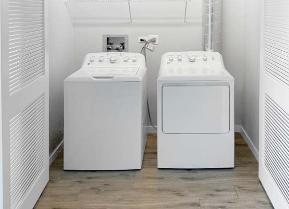 two washing machines in a laundry room with a wood floor