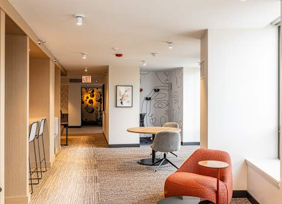 A hallway with a red chair and a white wall at Kingsbury Plaza, Chicago, IL, 60654