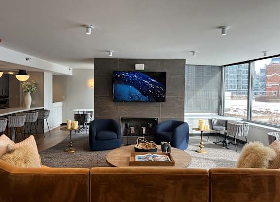 A modern living room with a large flat screen TV mounted above a fireplace at Kingsbury Plaza, Chicago