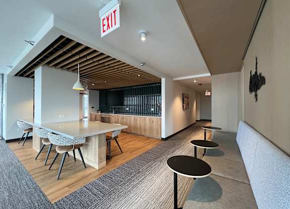 A room with a long table and chairs, a couch, and an exit sign at Kingsbury Plaza, Chicago, IL, 60654