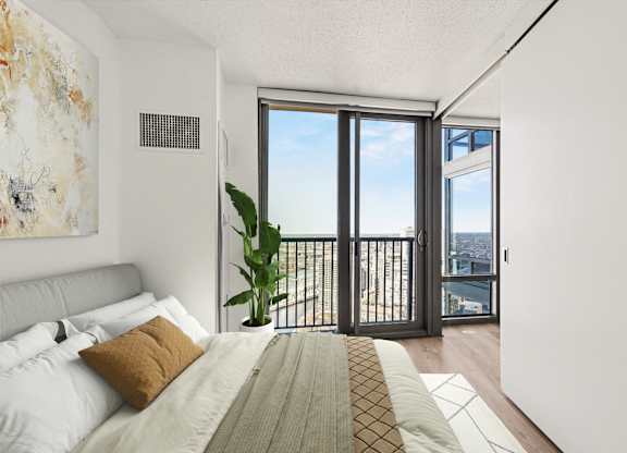 A bedroom with a large bed and a view of the city through the window.